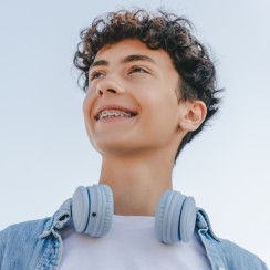 Junge mit Zahnspange lächelt vor blauem Himmel