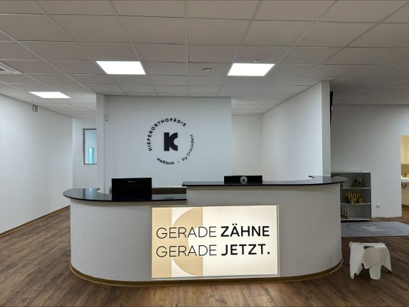 Anmeldungsthresen mit Leuchtschild "Gerade Zähne, Gerade jetzt"